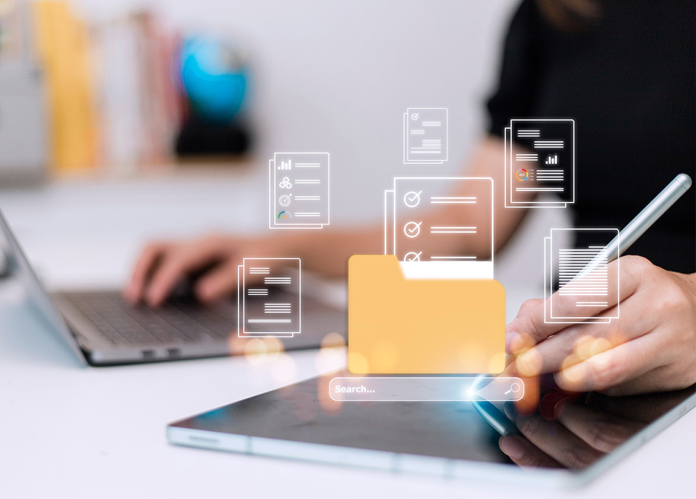 Business Technology | Close up of person working on laptop while writing on a tablet with icons floating in the air