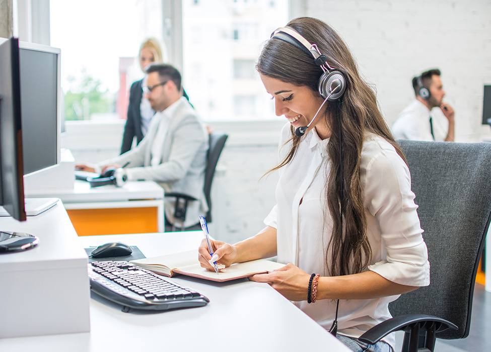 call center services | Customer Service rep wearing a headset and writing down notes