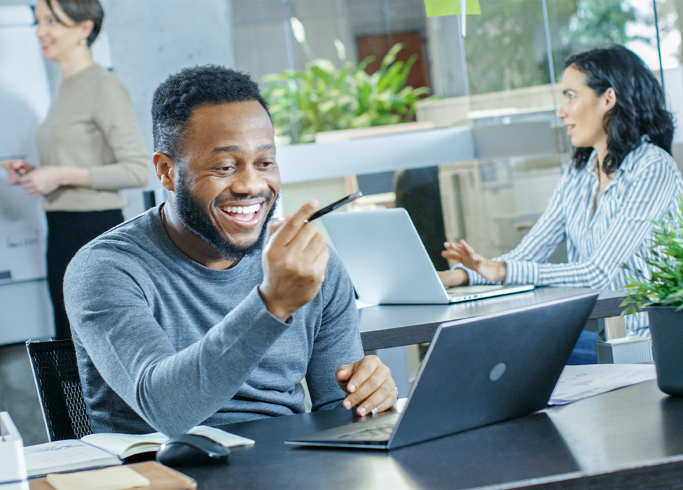 Hybrid working | Man smiling while working in the office on a laptop